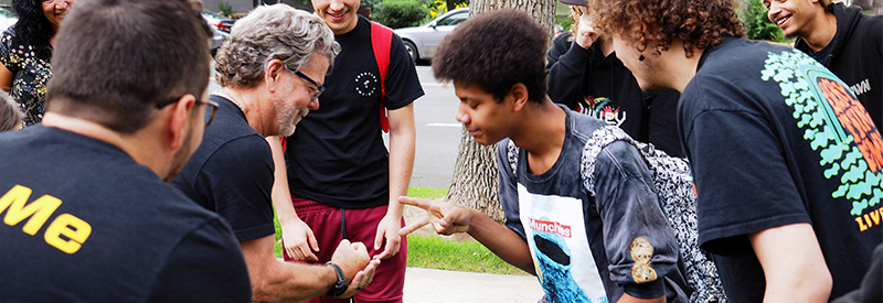 PSD high school students play rock, paper, scissors outside.