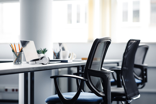 Chairs in front of a table with laptops and headphones.