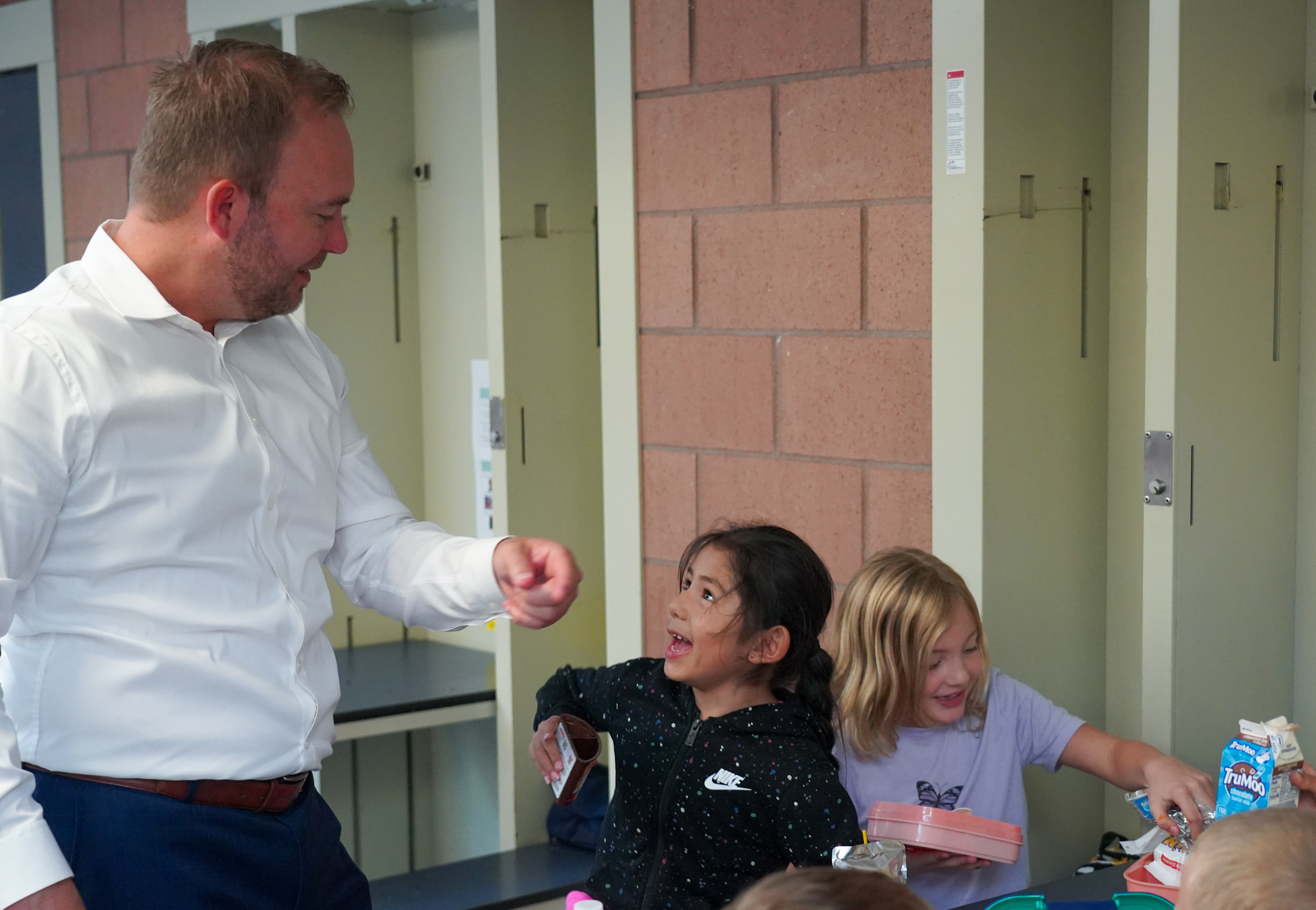 Superintendent Kingsley high fives elementary students in the cafeteria. 