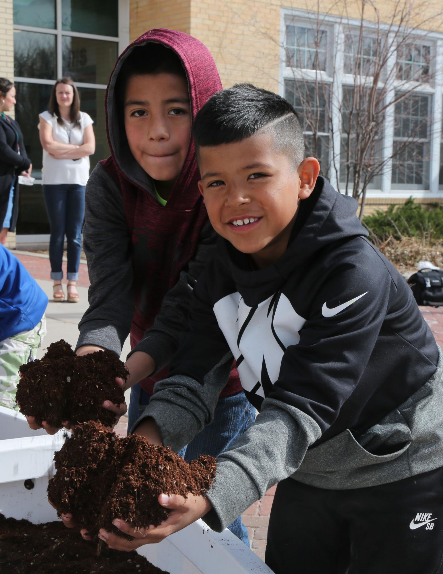 Two students hold seedlings