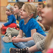 A young student listens while sitting on the floor. 