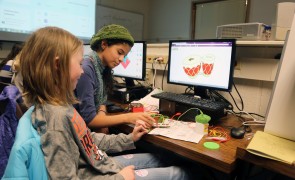 Two girls working on a creative project on a computer.